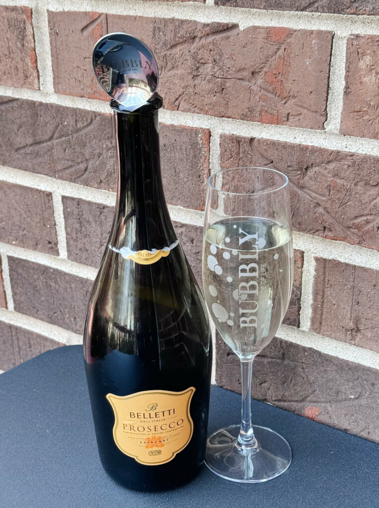 A bottle of Belletti Prosecco next to a champagne flute full of the prosecco wine.  